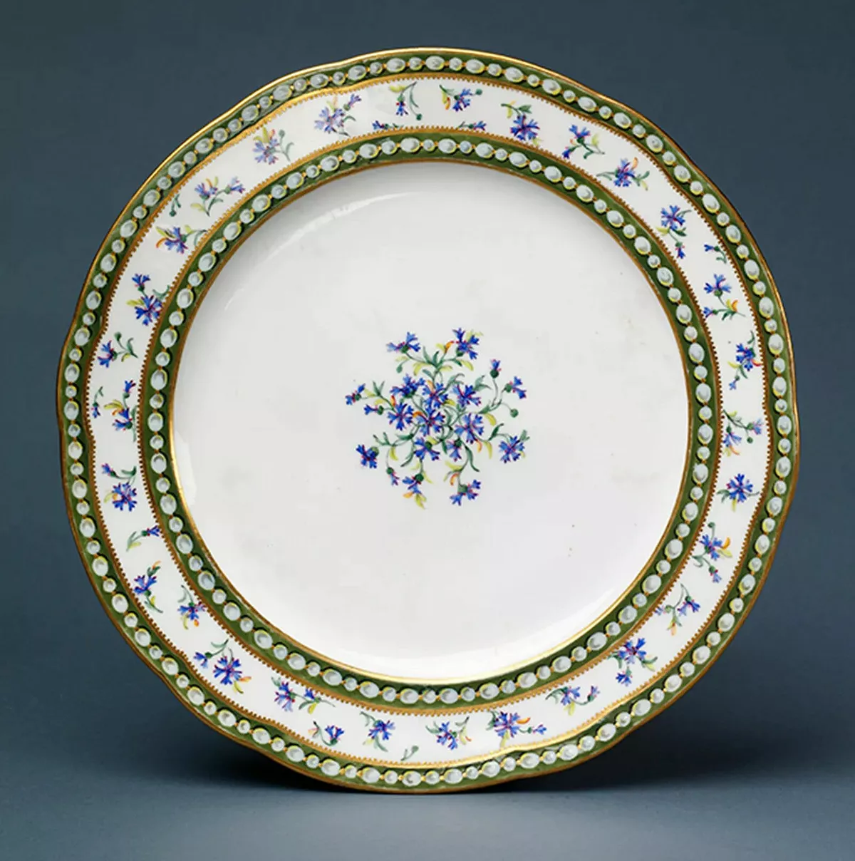 Тарелка с васильками. Севрская мануфактура, 1781 год. Мягкий фарфор, эмаль, золото. Размеры: 3,0 × 24,2 × 24,2 см. Коллекция Музея Виктории и Альберта.